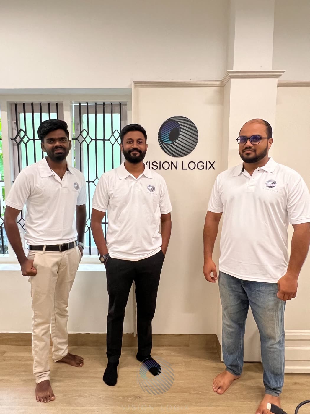 Three members of the Vision Logix team standing in front of the company sign at the office.